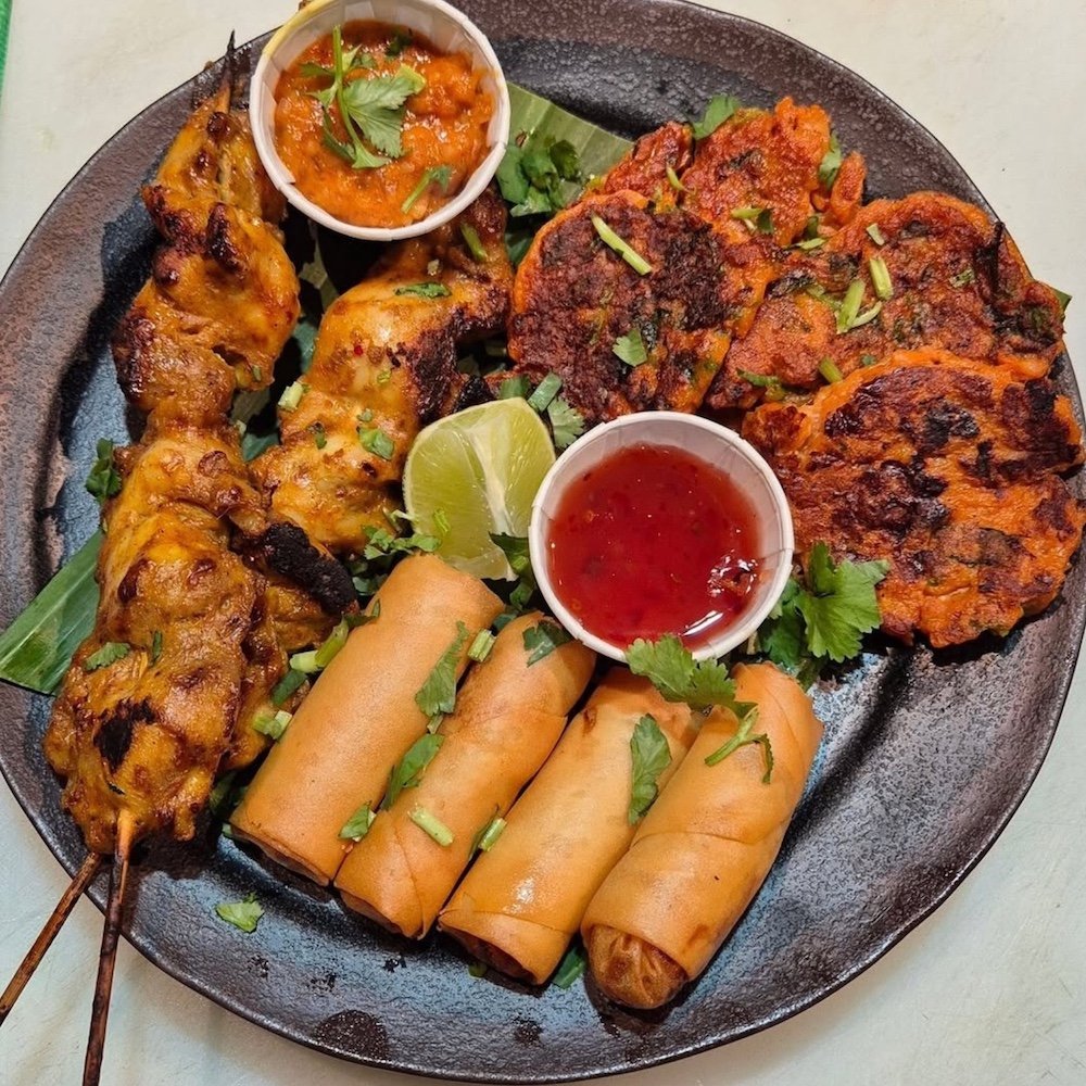 Platter of chicken satay, spring rolls and dipping sauces