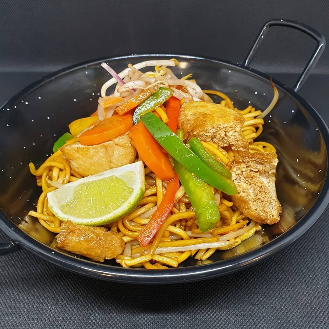 Colourful wok-fried noodles with vegetables and lime